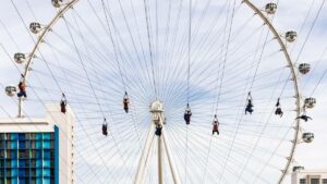 Several people gliding down a zipline in front of the LINQ wheel in Las Vegas